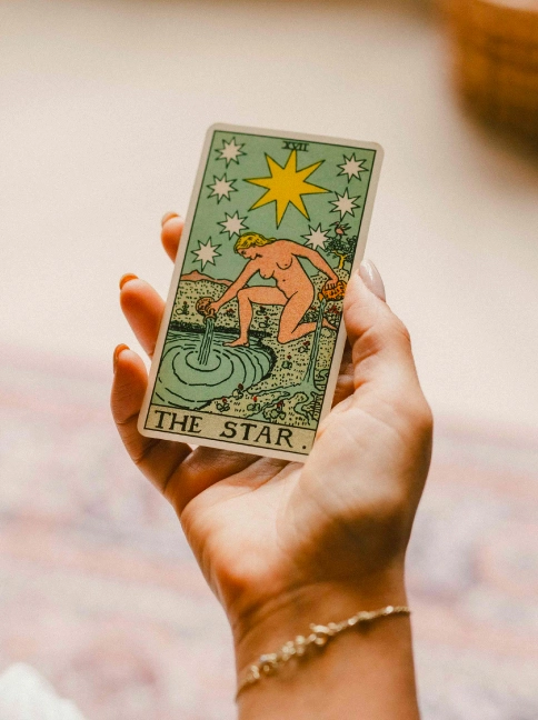 A hand holding The Star tarot card